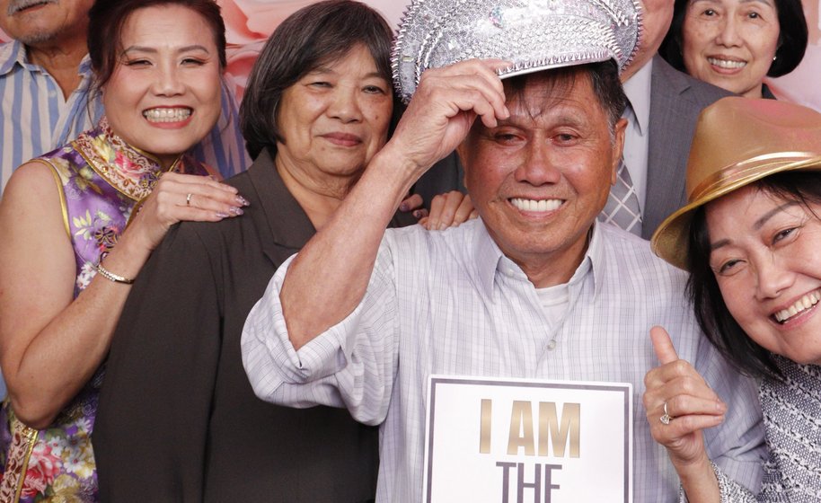 Group of wedding guests posing playfully at floral photo booth
