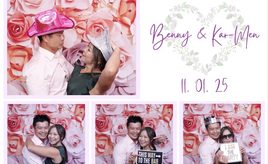 Couple posing playfully at wedding photo booth with floral backdrop